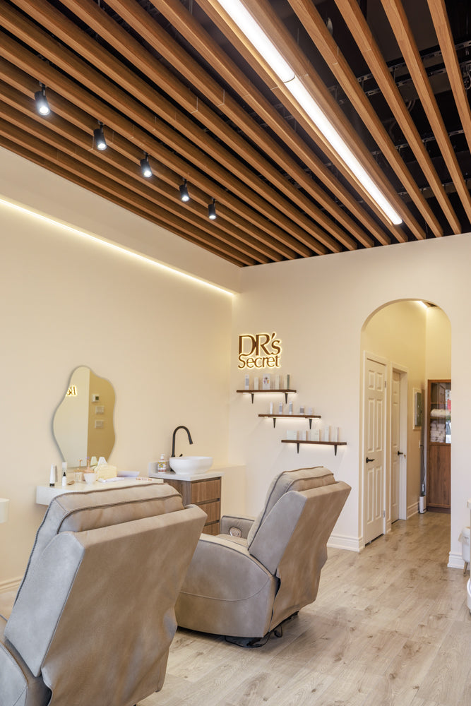 Wood-look ceiling strips with linear lights above grey salon chairs and cream walls