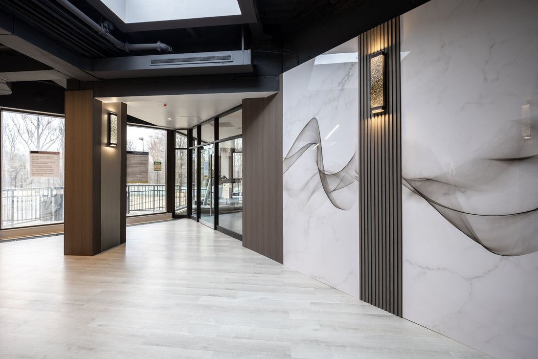 Hospitality lobby interior with marble-look large wall panels, dark slat details, and warm wood-tone wall surfaces