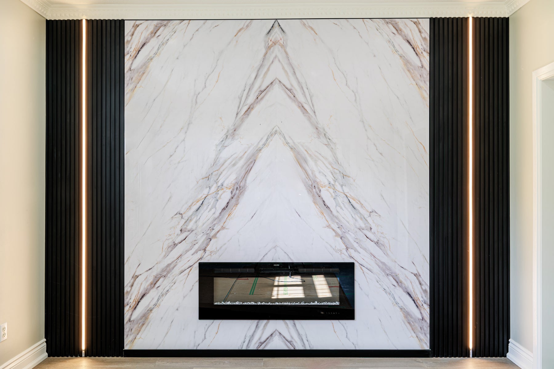 Alternate view of RichVaugh bookmatched marble and matte black slat fireplace feature wall in Oshawa Ontario