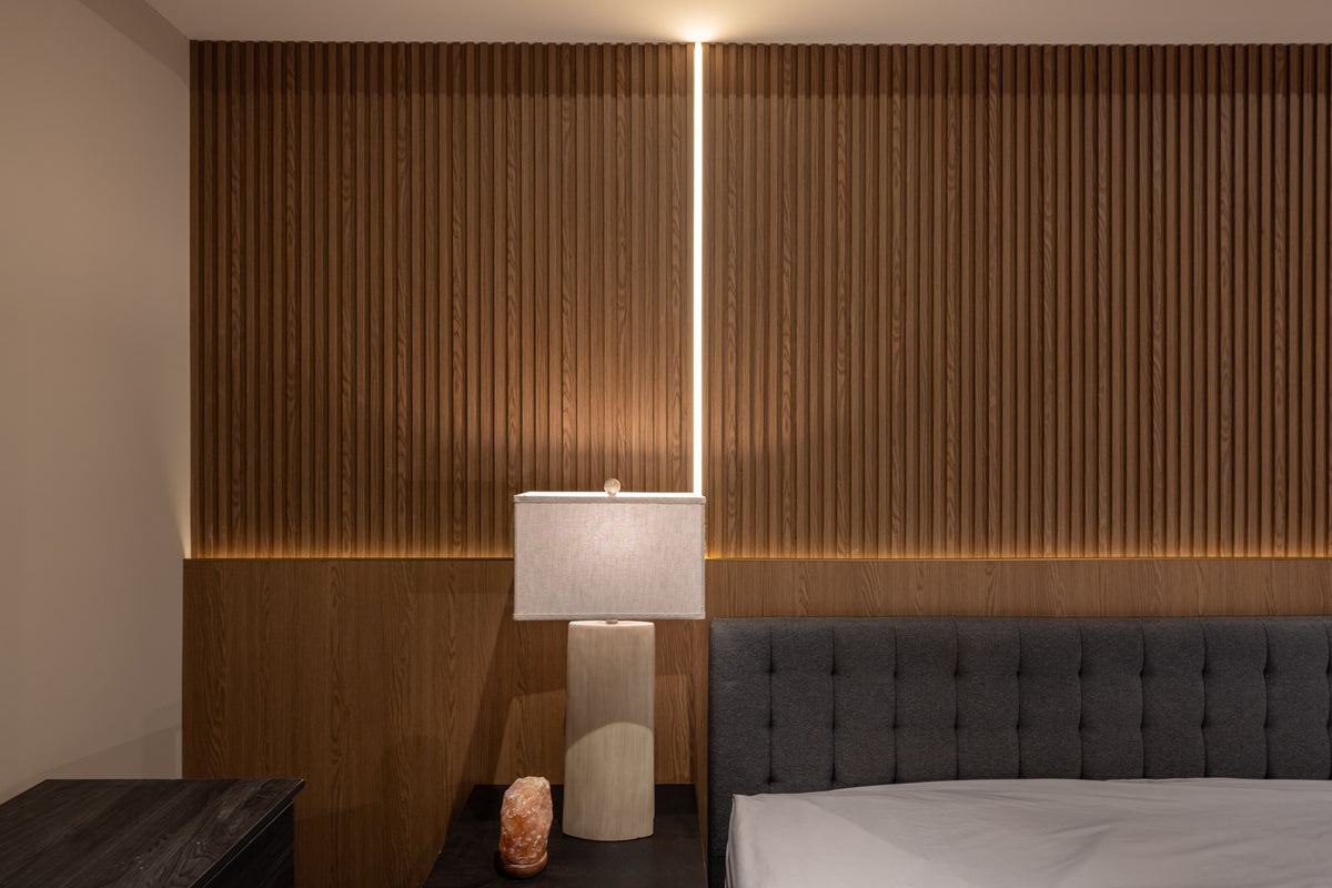 Close view of oak slat texture, a vertical LED strip and matching large wall panels in an Etobicoke bedroom.