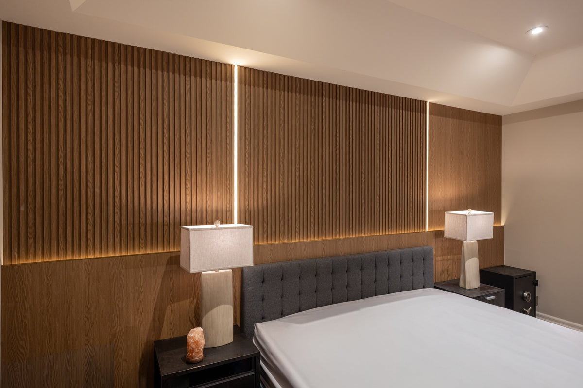 Angled view of oak slat and large wall panels behind a gray upholstered headboard in an Etobicoke bedroom.