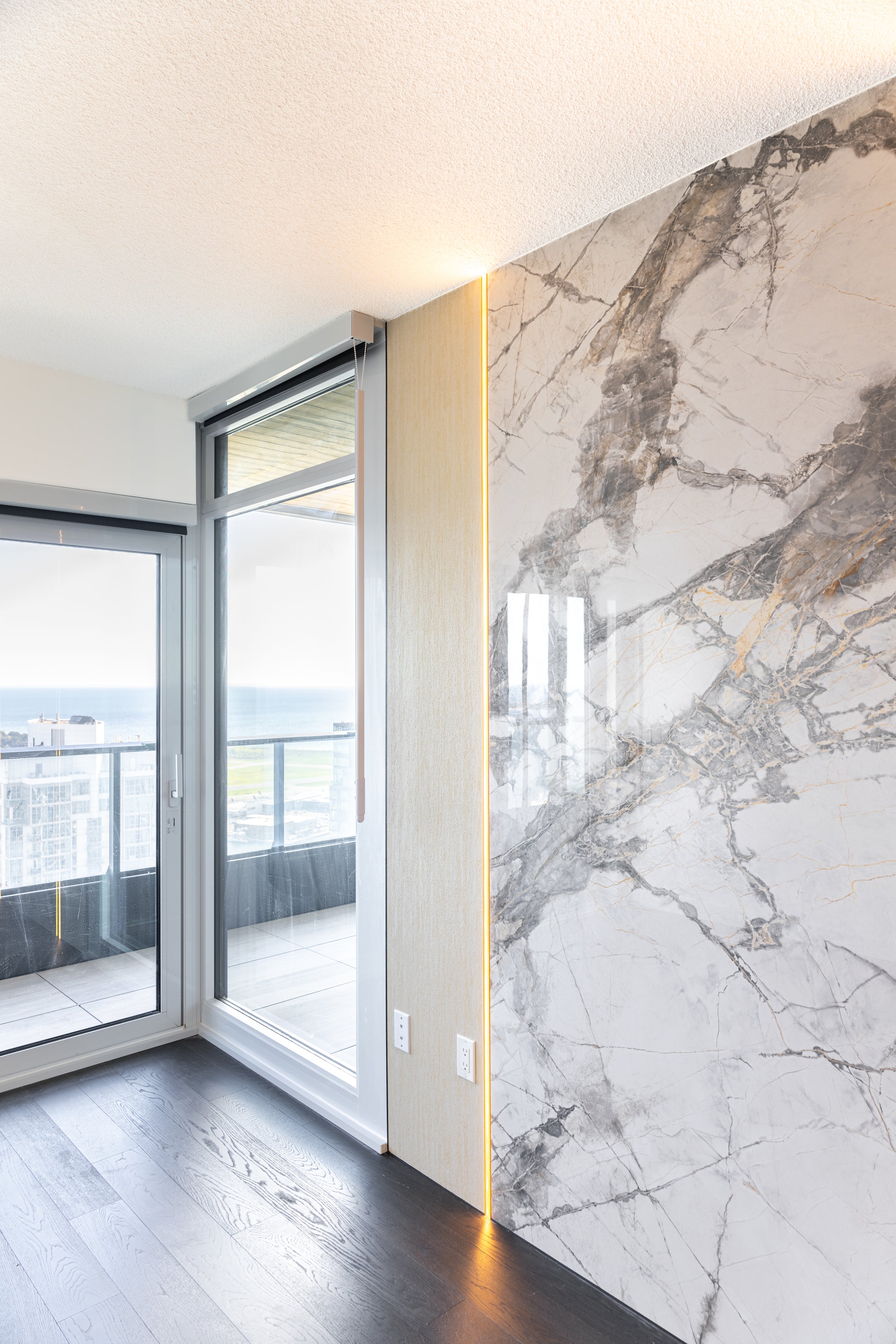 Close-up of Travertine Beige wall panels and a backlit marble-look feature wall in a luxury Toronto condo renovation.