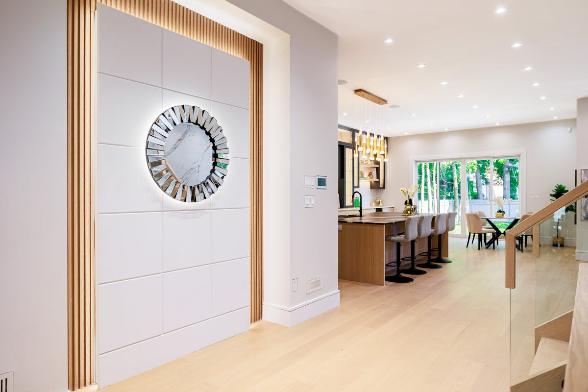 Markham foyer with a circular decorative mirror, smooth wall panels and wood-tone slat border.