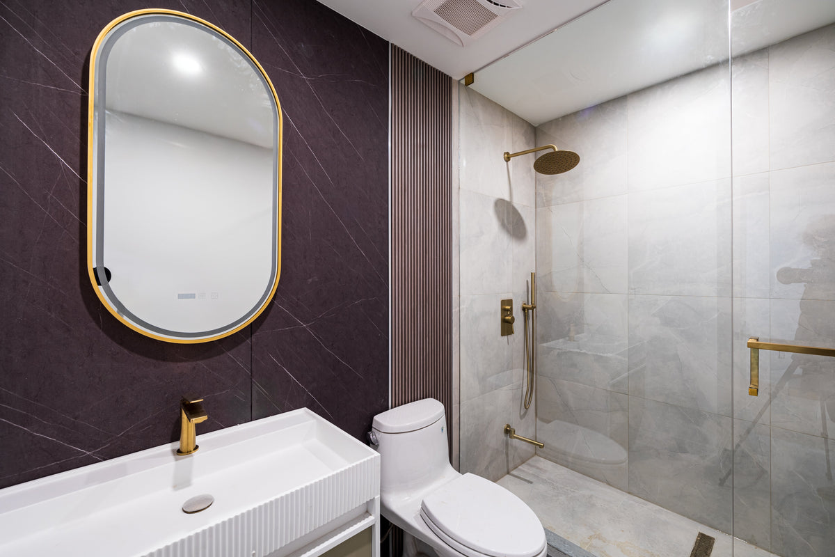 Markham bathroom with dark panel walls, a gold-framed mirror and glass shower.
