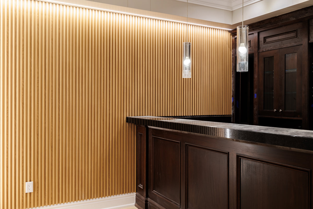 Natural Wood slat wall with warm lighting behind a dark basement bar in North York.