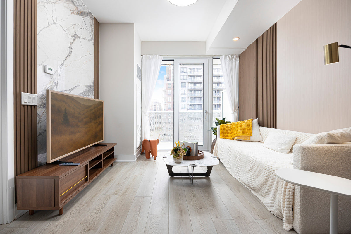 White sofa facing a wood-tone and marble-look TV feature wall in a North York condo.