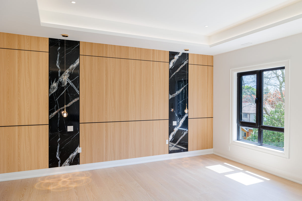North York custom home feature wall with natural wood-tone panels, black marble-look strips and wall sconces.