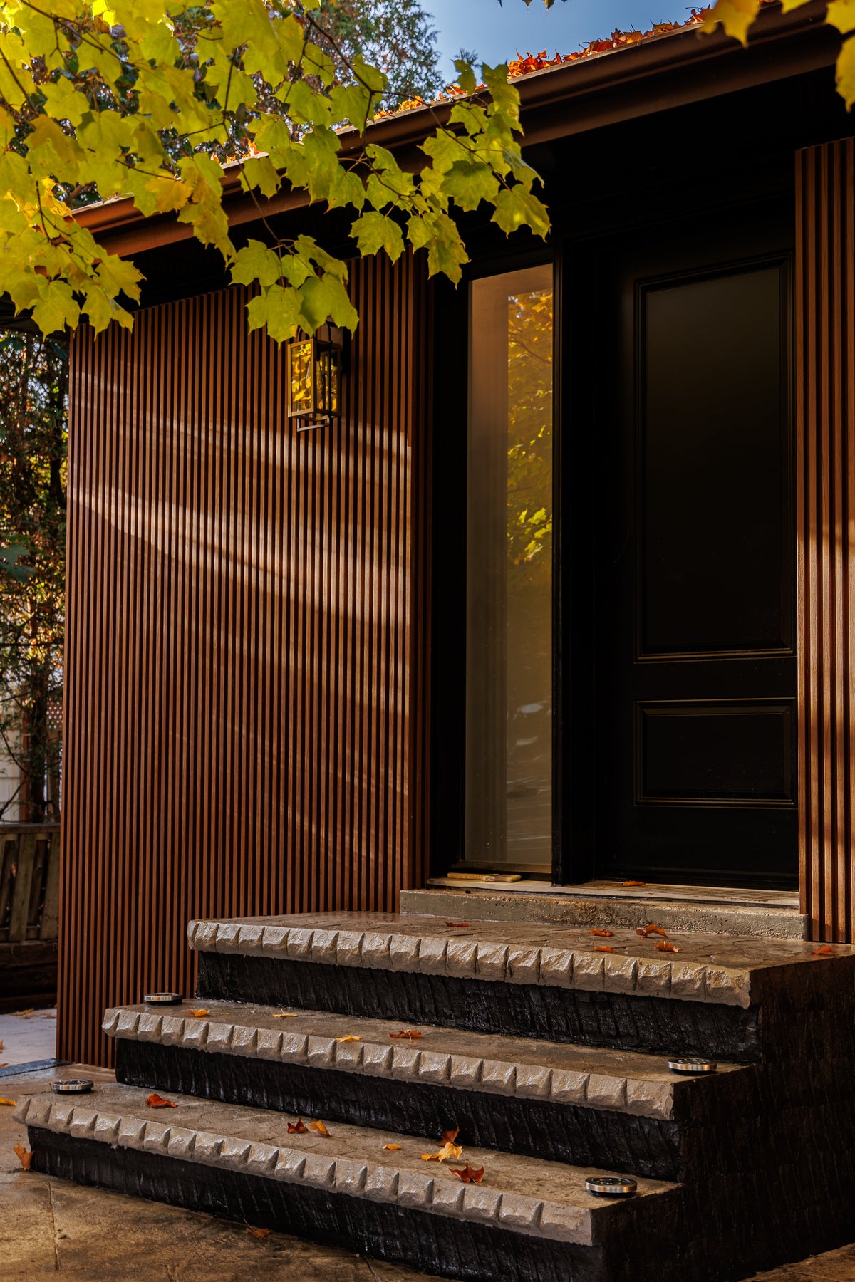 Pickering front entrance with Wood Brown vertical siding, a dark door and timber porch steps.