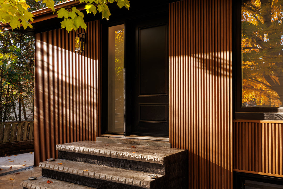 Close view of brown slat siding beside the front door and porch in Pickering.
