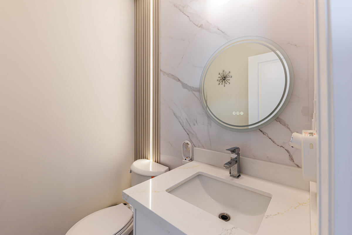 Richmond Hill bathroom vanity with a circular mirror, marble-look wall and illuminated slat detail.