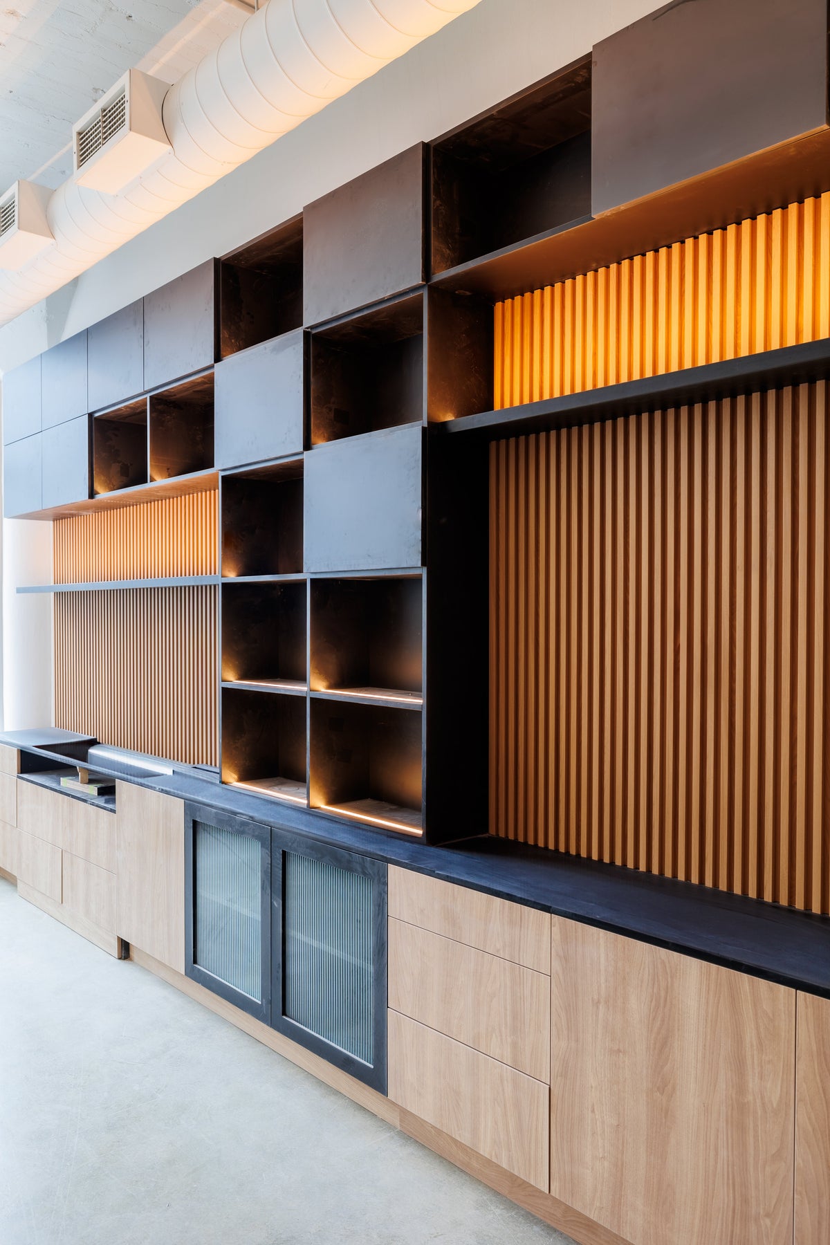 Built-in shelving with wood-tone slat panels and dark cabinets in a Toronto condo.