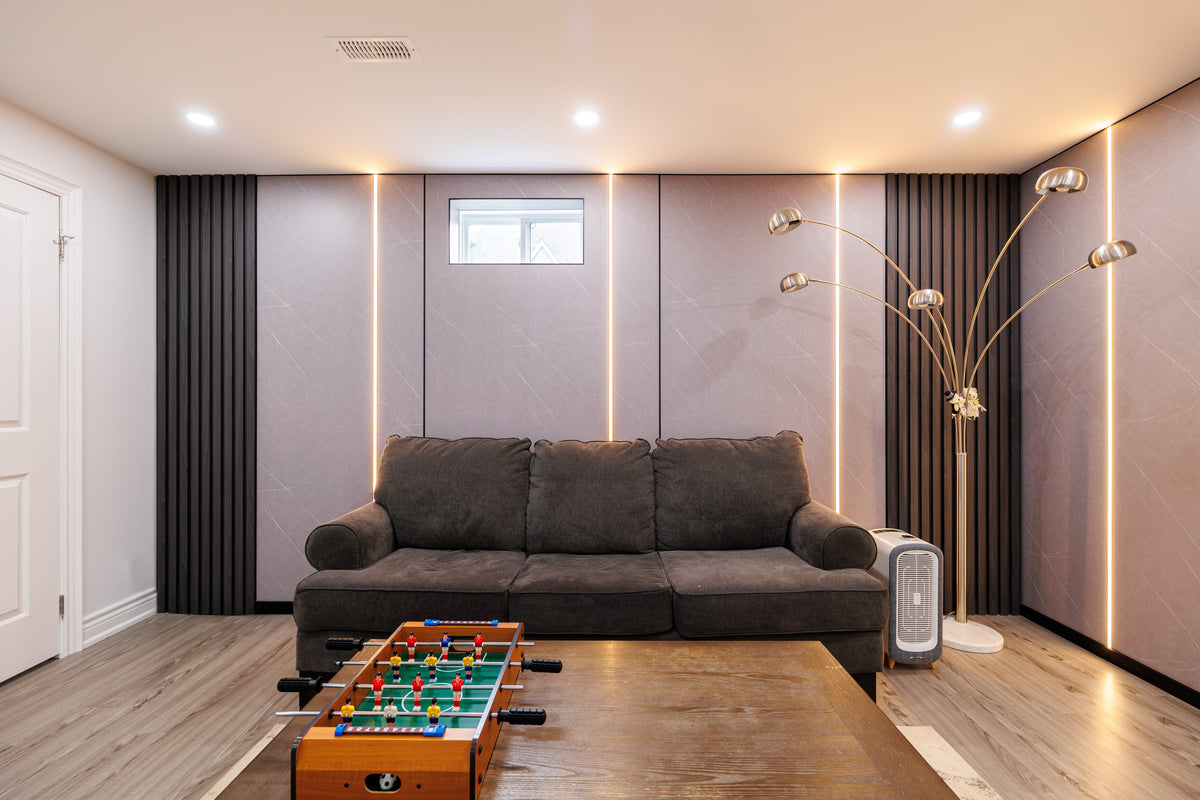Vaughan family room with gray wall panels, black slat accents and vertical light strips behind a sofa.